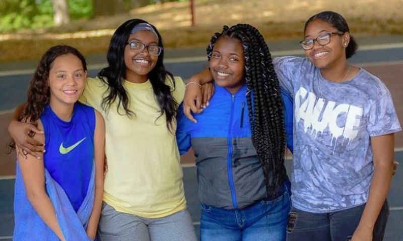 group of four girls with hands around each other